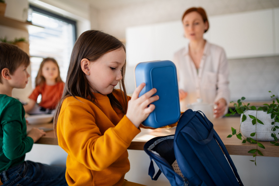 child putting school snacks in backpack